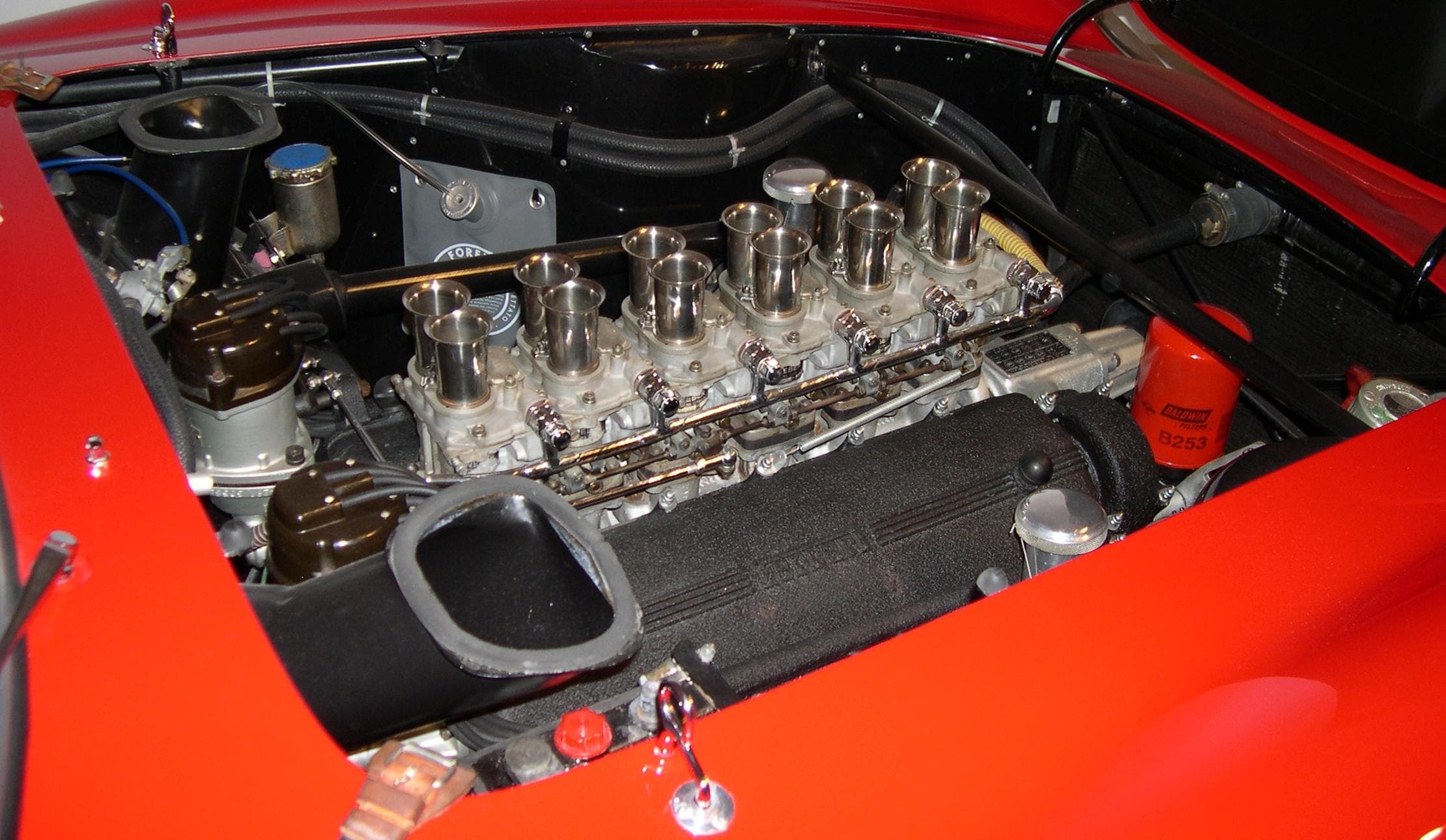 Ferrari V12 engine bay with six carburettors and their paired intake trumpets.