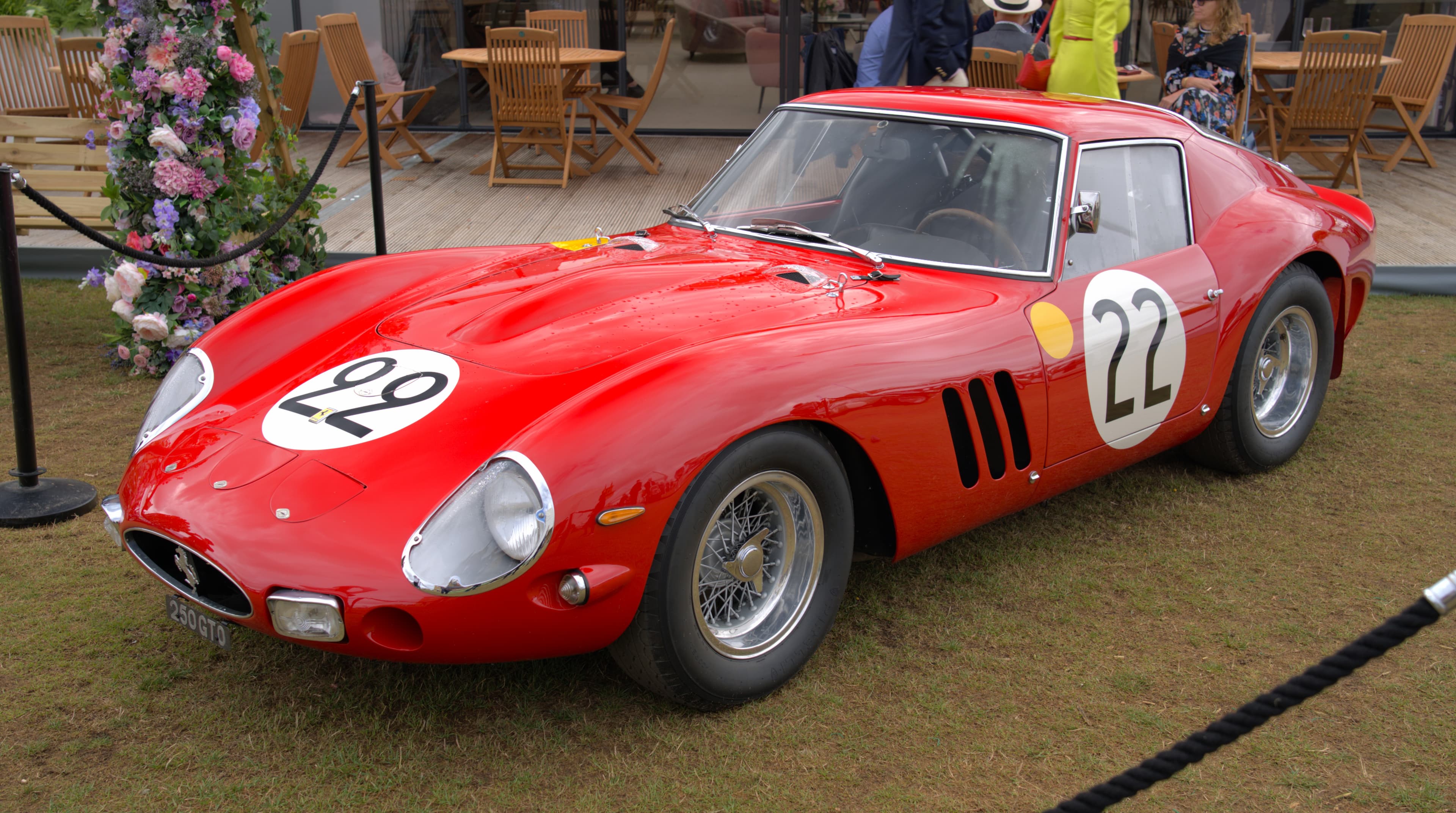 Red Ferrari 250 GTO with number 22, seen from the front left on a lawn at Salon Privé.